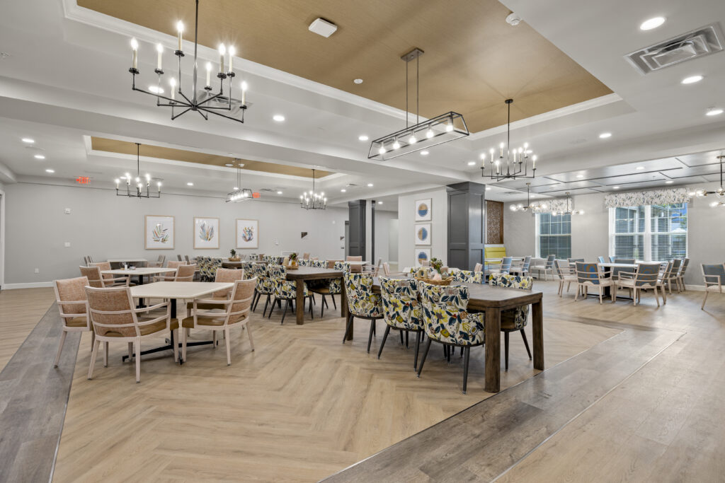 Large, inviting dining area showcasing chic seating arrangements, wood-style flooring, and elegant ceiling lighting.