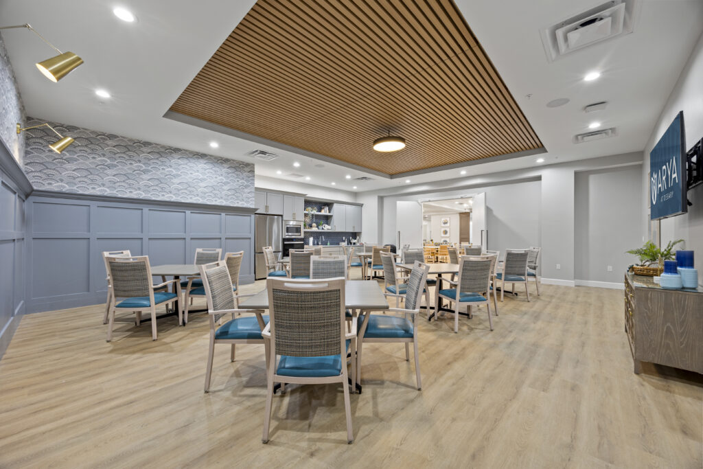 Chic activity room with soft blue accents, elegant wood ceilings, and versatile tables designed for social interactions.