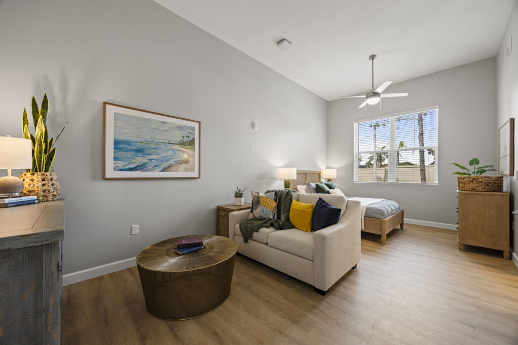 Modern studio apartment featuring comfortable seating, stylish bed, wooden furniture, and artwork.