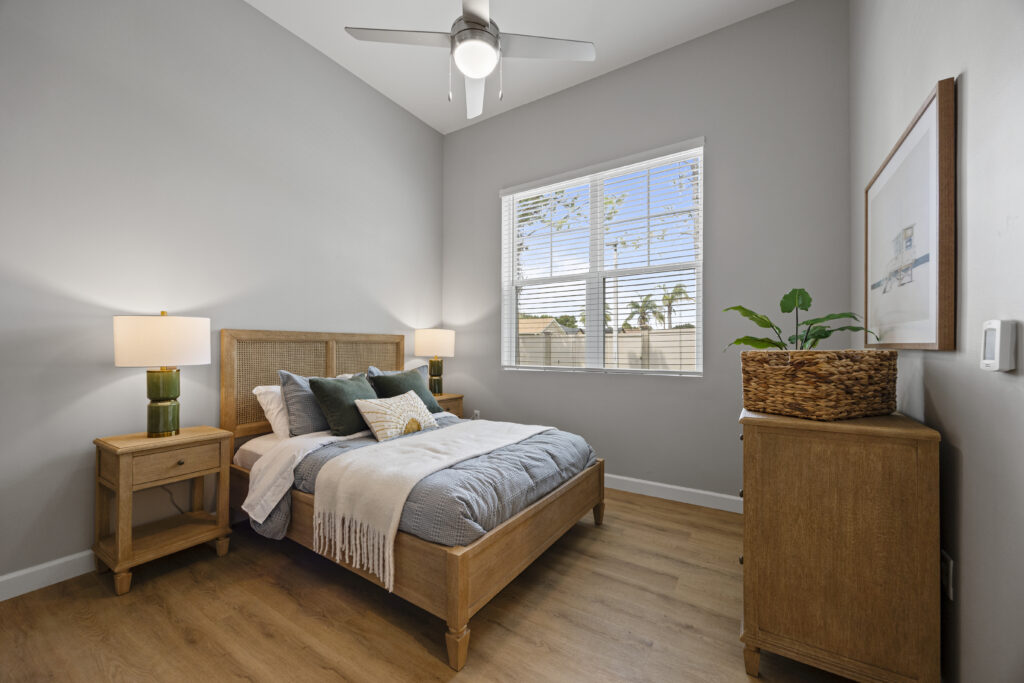 Cozy bedroom with ample natural light, tasteful décor, wooden furnishings, and greenery accents.