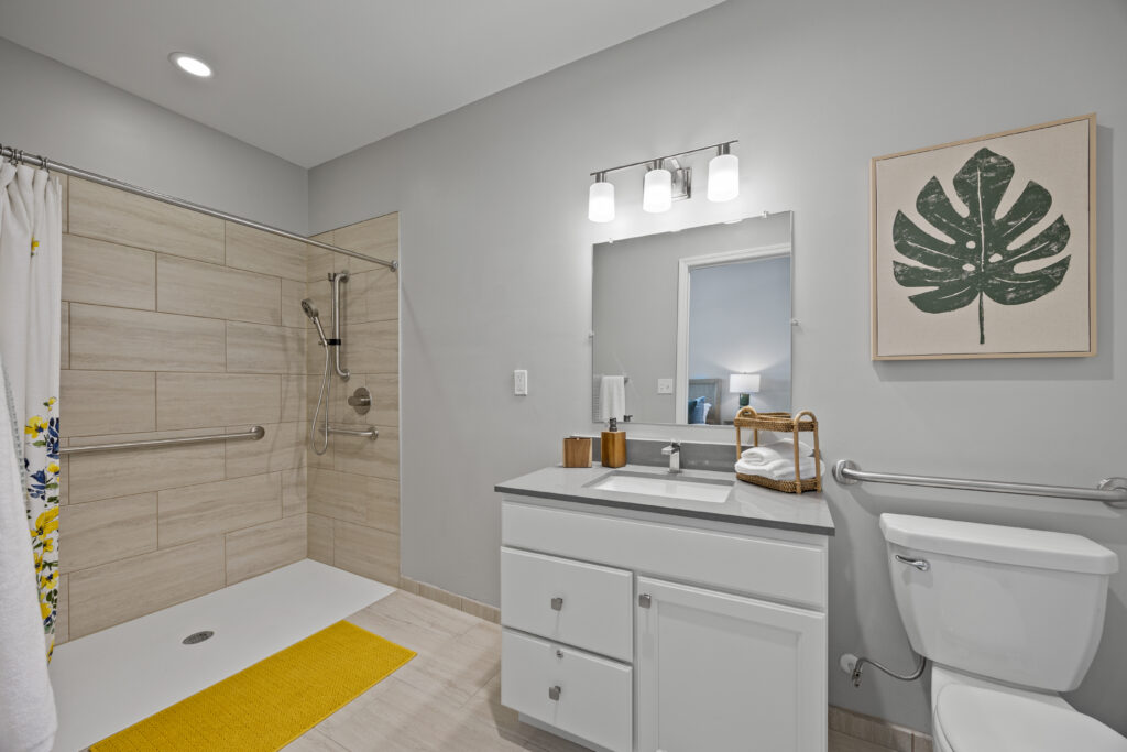 Accessible bathroom with spacious shower, grab bars, modern fixtures, and sleek design details.