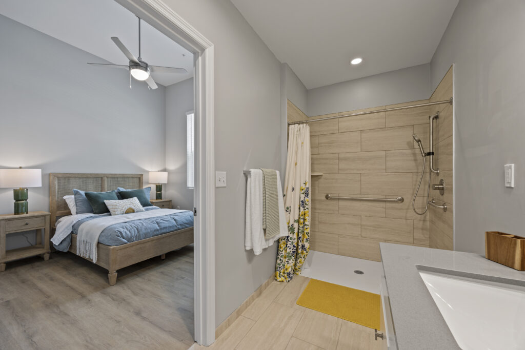 Bedroom view looking into an accessible bathroom featuring contemporary design and fixtures.