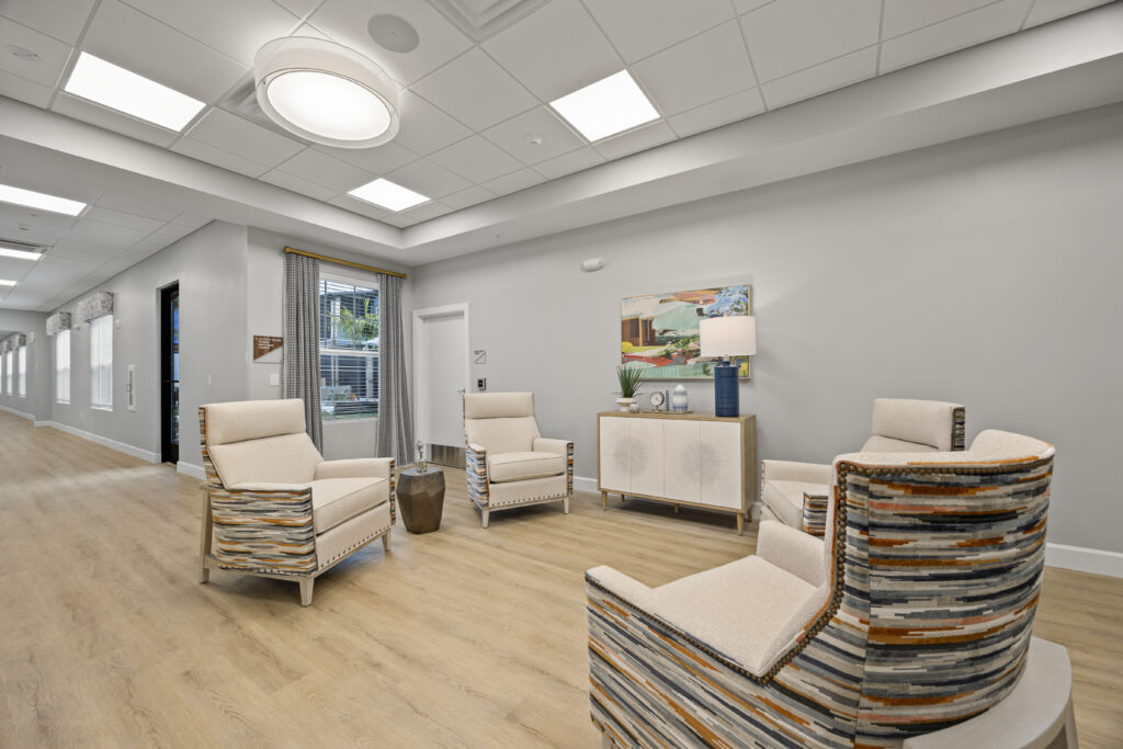 Bright hallway seating area with stylish armchairs, artwork, and a window showing greenery.