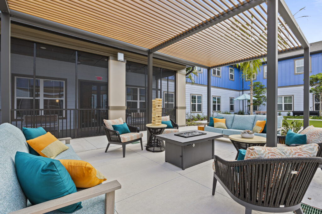 Outdoor patio with cushioned seating, a fire table, and pergola at Arya at DeBary.