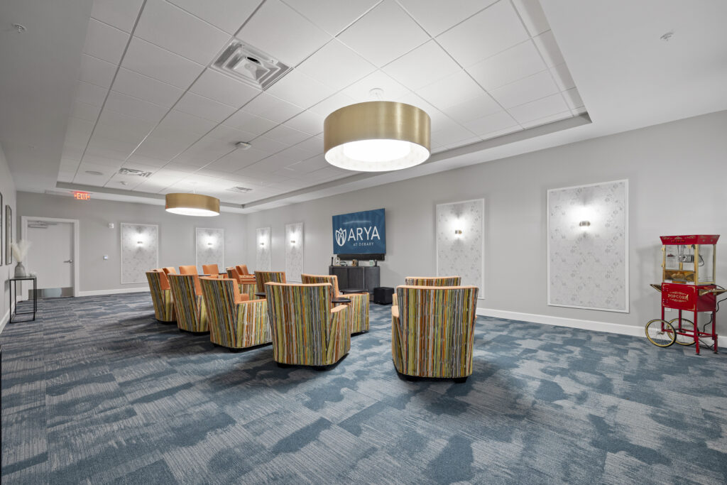 Spacious theater room with colorful seating, large TV, decorative wall panels, and popcorn machine.