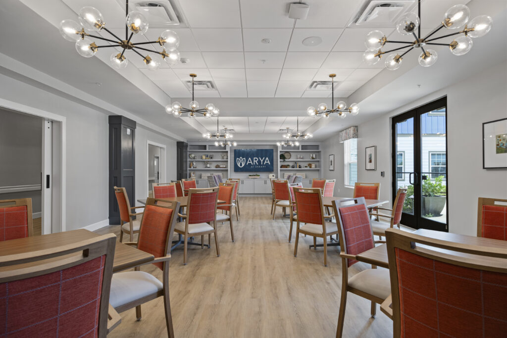 Wide view of a comfortable dining and gathering space with multiple tables and ambient lighting.