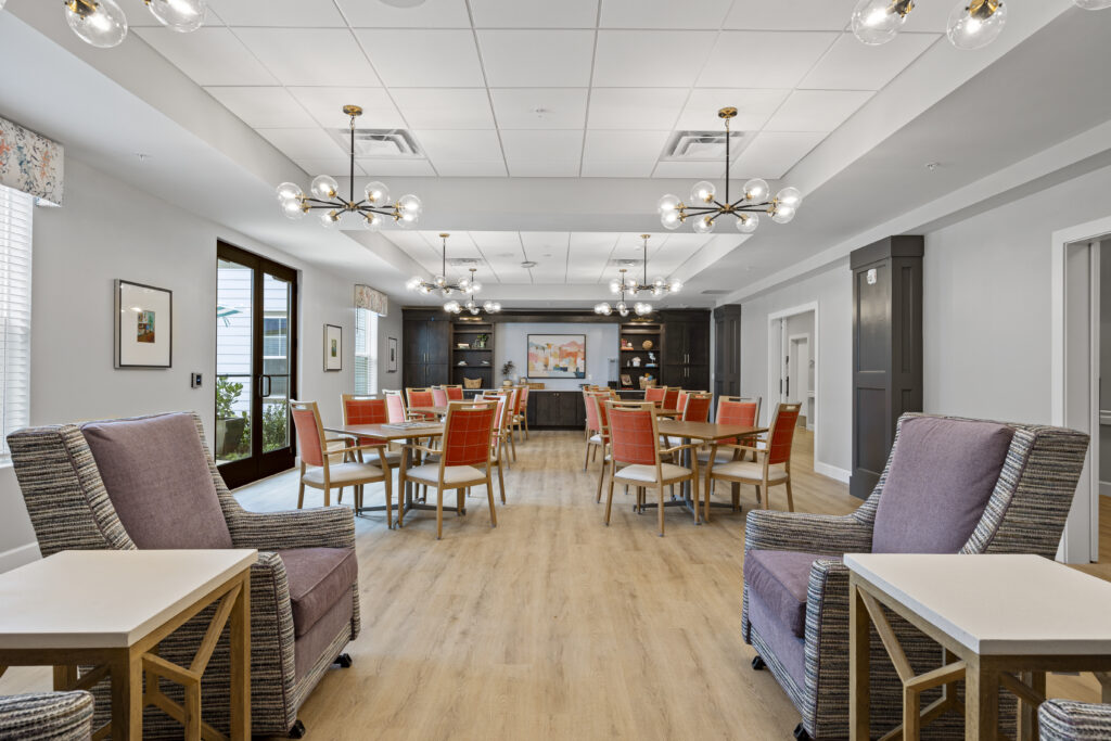 Dining room featuring stylish red chairs, unique chandeliers, and shelving units in the background.