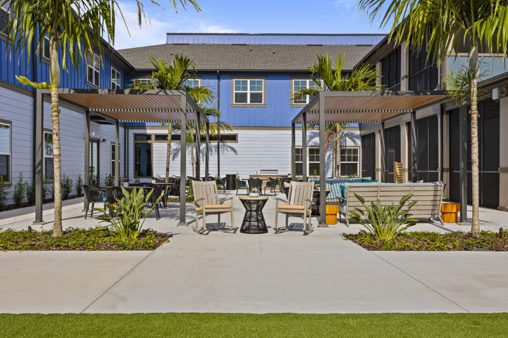 Open-air seating area with pergolas, palm trees, and benches at Arya at DeBary.